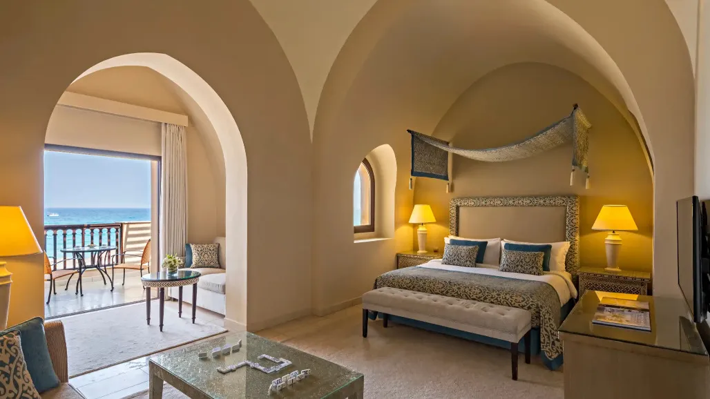 King-size bed, seating area and ocean-view balcony at Al Dhow Suite in Miramar Al Aqah Resort