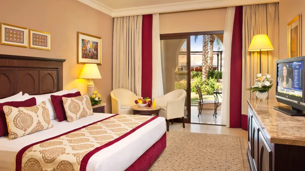 Queen size bed and two chairs at the Standard Room in Miramar Al Aqah Beach Resort